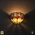 Tiffany wandlamp Giglio Rubino verlicht op muur – halfronde kap met rode bloemen en warme ambertinten