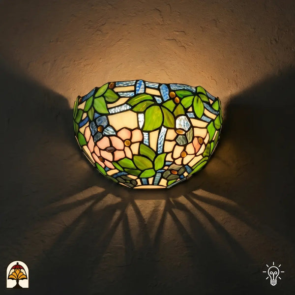 Tiffany wandlamp Rosa di Primavera verlicht op muur – roze bloemen en groene bladeren in glas-in-lood